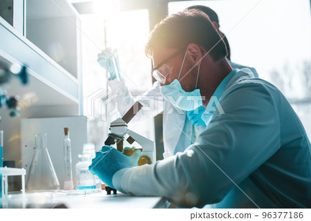 Doctor in the laboratory analyzes samples of codiv-9 under a microscope 96377186