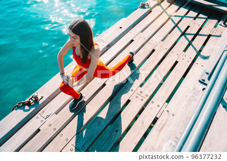 Woman does gym stretching exercises outdoor in a sunny day 96377232