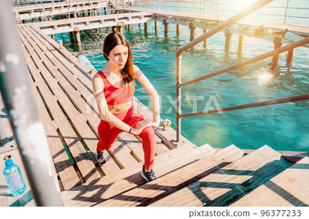 Woman does gym stretching exercises outdoor in a sunny day Woman does gym stretching exercises outdoor in a sunny day 96377233