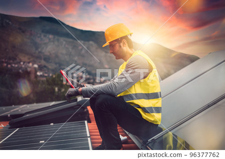 Man works on renewable energy system with solar panel for electricity and hot water 96377762