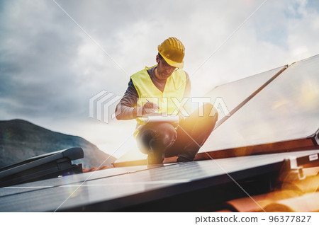 Man works on renewable energy system with solar panel for electricity and hot water 96377827