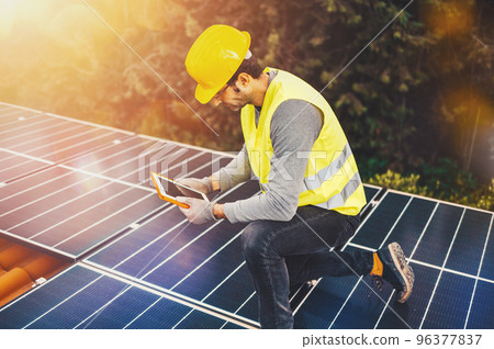 Workers verify energy system with solar panel with a tablet Workers verify energy system with solar panel with a tablet 96377837