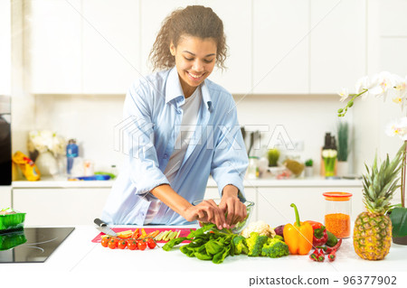 Young woman in the home kitchen prepares a genuine salad with fresh vegetables 96377902