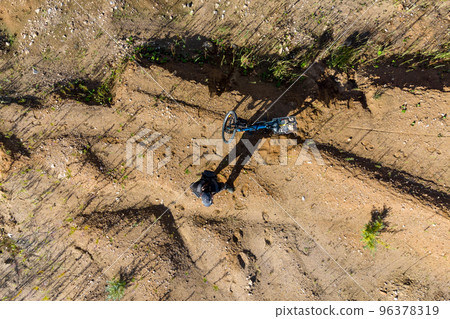 Top view of a man with a bicycle in the middle of a sandy landscape 96378319