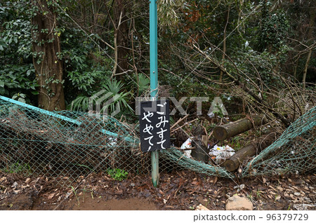A large amount of garbage dumped on the side of a dimly lit road A large amount of garbage dumped on the side of a dimly lit road 96379729
