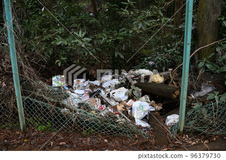 A large amount of garbage dumped on the side of a dimly lit road 96379730