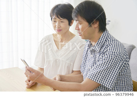 Mature couple using smartphone at home Mature couple using smartphone at home 96379946