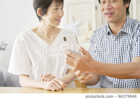 Mature couple using smartphone at home 96379948