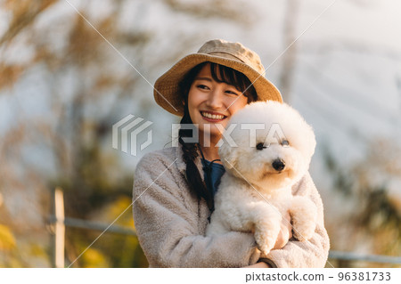 Camper Asian woman holding her pet dog at a campsite in autumn and winter (Vision Frise) 96381733