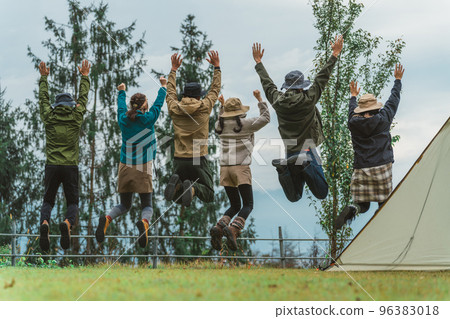 Back view of friends and friends jumping at a campsite in autumn and winter Back view of friends and friends jumping at a campsite in autumn and winter 96383018