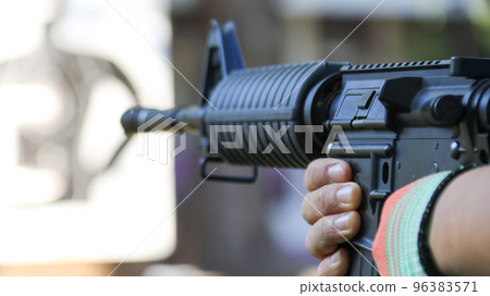 Air soft gun holding by hands aiming at the blur shooting target in the shooting range, soft and selective focus on the gun                               96383571