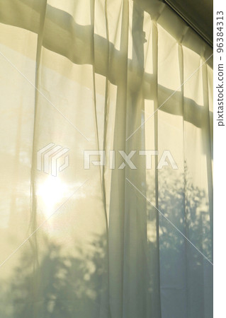 Curtains that let the light of the setting sun through 96384313