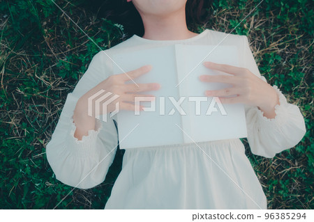 一名年輕女子躺下看書的照片 一名年輕女子躺下看書的照片 96385294
