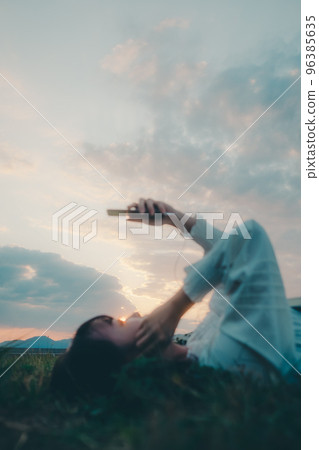 Photo of a young woman lying down and listening to music Photo of a young woman lying down and listening to music 96385635