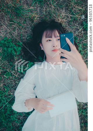 一位年輕女子躺下聽音樂的照片 96385718