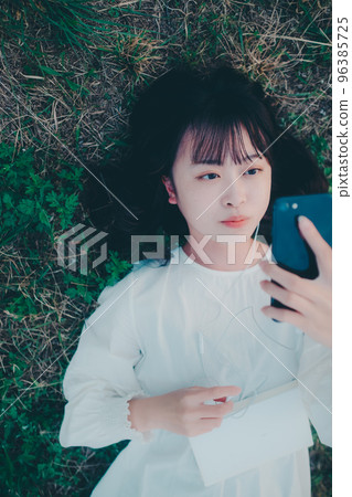 Photo of a young woman lying down and listening to music Photo of a young woman lying down and listening to music 96385725