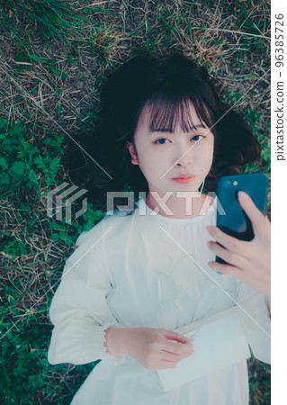 Photo of a young woman lying down and listening to music 96385726