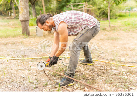 Man cutting a piece of iron using a radial saw 96386301