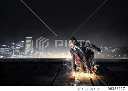 Determined businessman leaving fire trails on asphalt 96387637