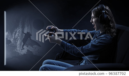 A woman in headphones with a controller set aside in her hands A woman in headphones with a controller set aside in her hands 96387702