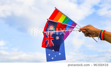 LGBT rainbow flag holding by hand with blue sky in background to enhance LGBTQ community around the world LGBT rainbow flag holding by hand with blue sky in background to enhance LGBTQ community around the world 96388416