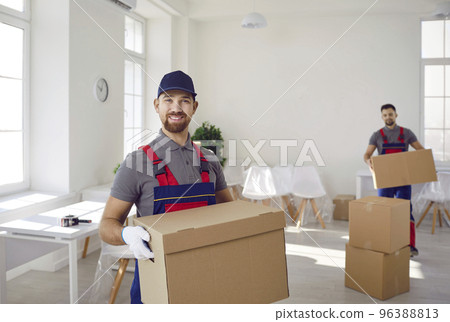 Portrait of smiling male loader with colleague taking cardboard boxes out of client's house. Portrait of smiling male loader with colleague taking cardboard boxes out of client's house. 96388813