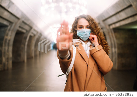 Girl in protective sterile medical mask on her face at empty subway station. Woman, wear face mask Girl in protective sterile medical mask on her face at empty subway station. Woman, wear face mask 96388952