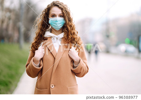 Woman in protective medical mask on her face on the street. Woman, wear face mask. Corona virus. Woman in protective medical mask on her face on the street. Woman, wear face mask. Corona virus. 96388977