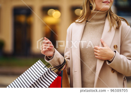 Shopping bags in the hands. Hand of young woman with multi-coloured bags with purchases. Shopping bags in the hands. Hand of young woman with multi-coloured bags with purchases. 96389705