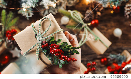 Hand holding Christmas present on the table Hand holding Christmas present on the table 96389990