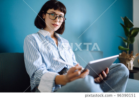 Young woman using tablet, spending leisure time chatting in social network. 96390151