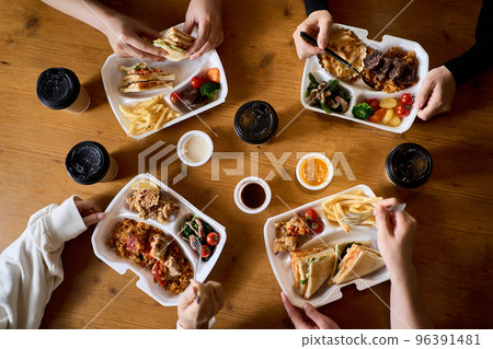 Hands of women eating takeout 96391481
