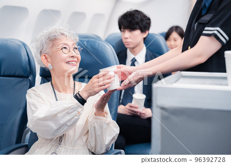 Cabin attendant serving drinks onboard Cabin attendant serving drinks onboard 96392728