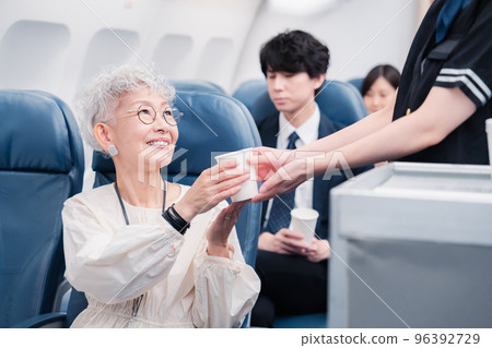 Cabin attendant serving drinks onboard Cabin attendant serving drinks onboard 96392729