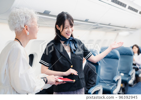 Cabin attendant guiding passengers to their seats 96392945
