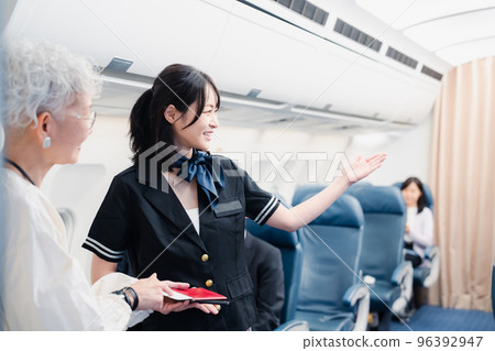 Cabin attendant guiding passengers to their seats 96392947