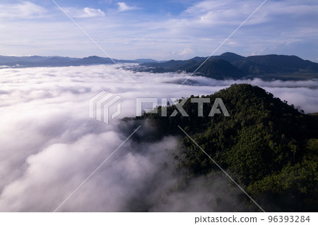 Aerial view of flowing fog waves on mountain tropical rainforest,Bird eye view image over the clouds Amazing nature background with clouds and mountain peaks in Thailand 96393284