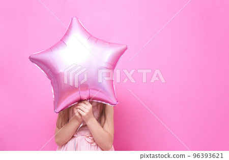 An unrecognisable girl stands and holds a balloon in the shape of a star, covering her face. The concept of a holiday with balloons with space to copy. High quality photo 96393621
