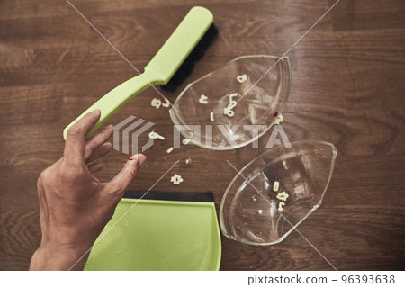 Close-up of a cut female finger on the background of a split cup and a brush with a dustpan for cleaning. A wound with blood received when cleaning broken dishes. High quality photo 96393638