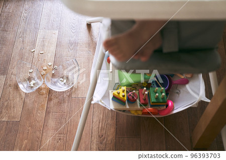 A small baby on a high chair dropped a cup of noodle soup on the wooden floor. The transparent plate is divided into two parts. Noodles in the form of figures. The table is dirty. High quality photo A small baby on a high chair dropped a cup of noodle soup on the wooden floor. The transparent plate is divided into two parts. Noodles in the form of figures. The table is dirty. High quality photo 96393703