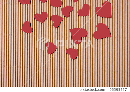 Red color paper hearts on a brown cardboard 96395557