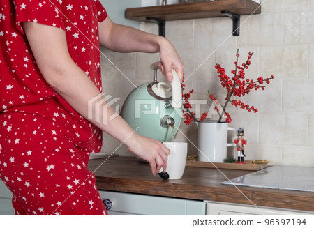 Female hands pouring tea at home kitchen table in winter in morning Female hands pouring tea at home kitchen table in winter in morning 96397194