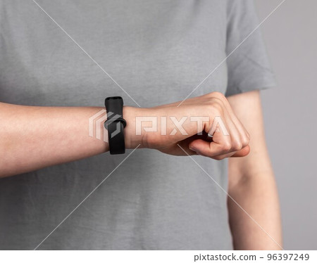 Woman looking at fitness tracker for checking physical activity results. Female with band at wrist for walking steps, running distance, heart rate or sleep patterns monitoring. Woman looking at fitness tracker for checking physical activity results. Female with band at wrist for walking steps, running distance, heart rate or sleep patterns monitoring. 96397249