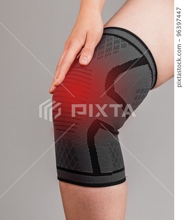 Woman wearing knee brace to reduce pain or prevent injury during sport. Female leg with red point. Sprained, ruptured ligaments, meniscus tear, tendinitis, arthritis. 96397447