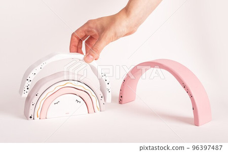 Woman putting arcs together in rainbow stacker. Wooden toy for kids for imagination, motor skills, sense of comparison development. 96397487