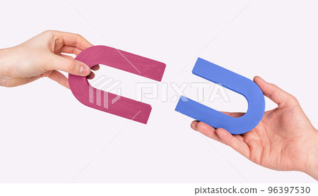 Magnets in man and woman hands. Love and relationship concept. Symbol of magnetic attraction between lovers Magnets in man and woman hands. Love and relationship concept. Symbol of magnetic attraction between lovers 96397530
