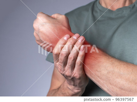 Man suffering from wrist pain and holding painful hand with red spot closeup. Hand injury. Health care, medicine concept 96397567