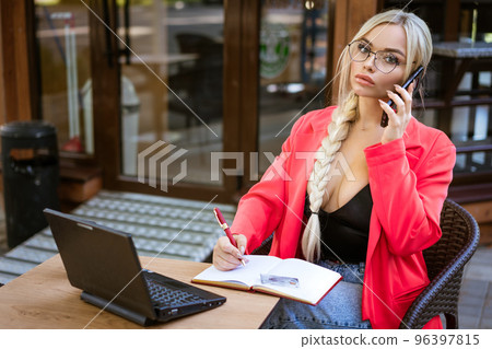 Young beautiful woman sitting at a table with a laptop on the street in a cafe 96397815