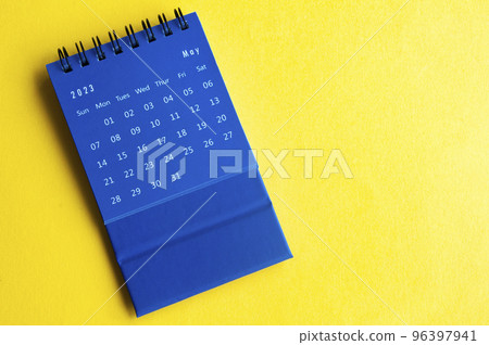 May 2023 blue desk calendar on yellow cover background with customizable space for text. 96397941
