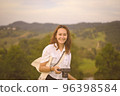 Happy smiling young woman traveller hand holding her camera 96398584
